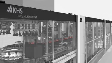 Die Abbildung zeigt eine KHS Innopack Kisters CNP Maschine, die für das Verpacken von Produkten in Karton verwendet wird, mit Einblick in den Produktionsprozess durch transparente Seitenwände.