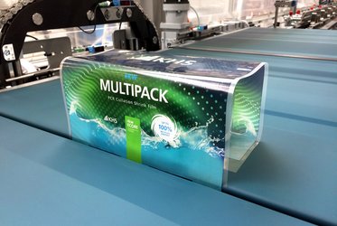 Eine Verpackung mit der Aufschrift "RKW Multipack" befindet sich auf einem Förderband während des Verpackungsprozesses und die Folie weist auf ihre 100 % Recyclingfähigkeit hin.