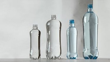 Das Bild zeigt verschiedene transparente Kunststoffflaschen in unterschiedlichen Formen und Größen, die auf einem weißen Hintergrund angeordnet sind und modernes Behälterdesign von KHS veranschaulichen.