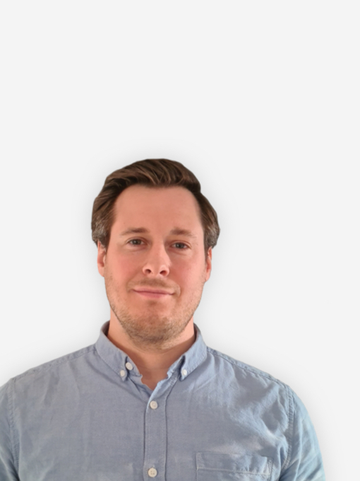 Das Bild zeigt den KHS-Kontakt Nils Schneider, einen Mann mit kurzem braunem Haar, der ein hellblaues Hemd trägt und vor einem schlichten, weißen Hintergrund steht und freundlich in die Kamera blickt.