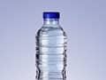 Clear plastic water bottle with a blue cap against a neutral background.